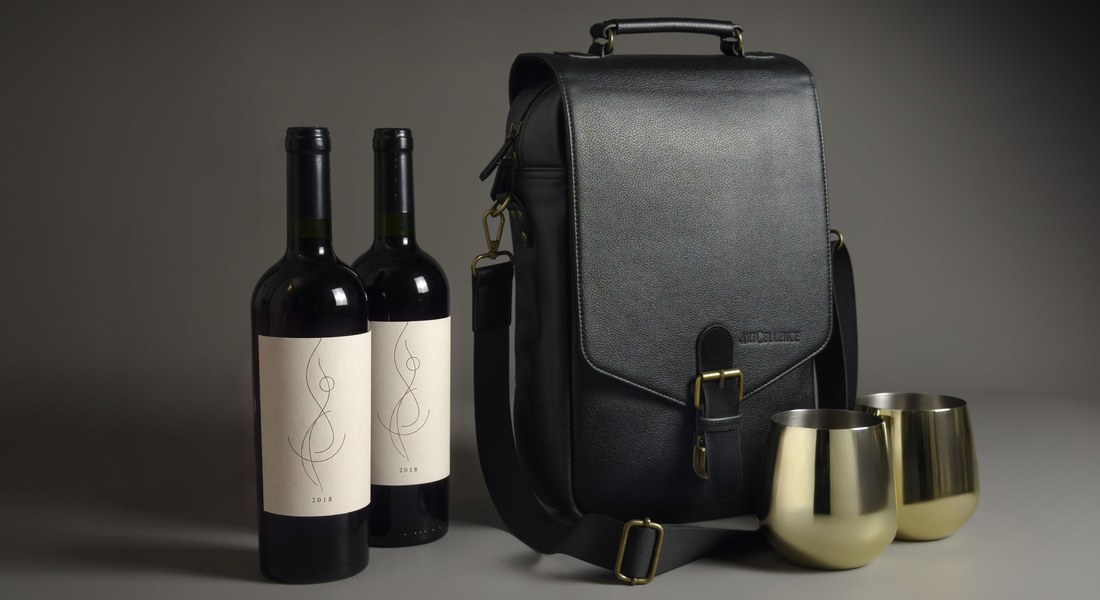 Black Artcellence wine carrier with two bottles and two gold steel glasses in a grey studio